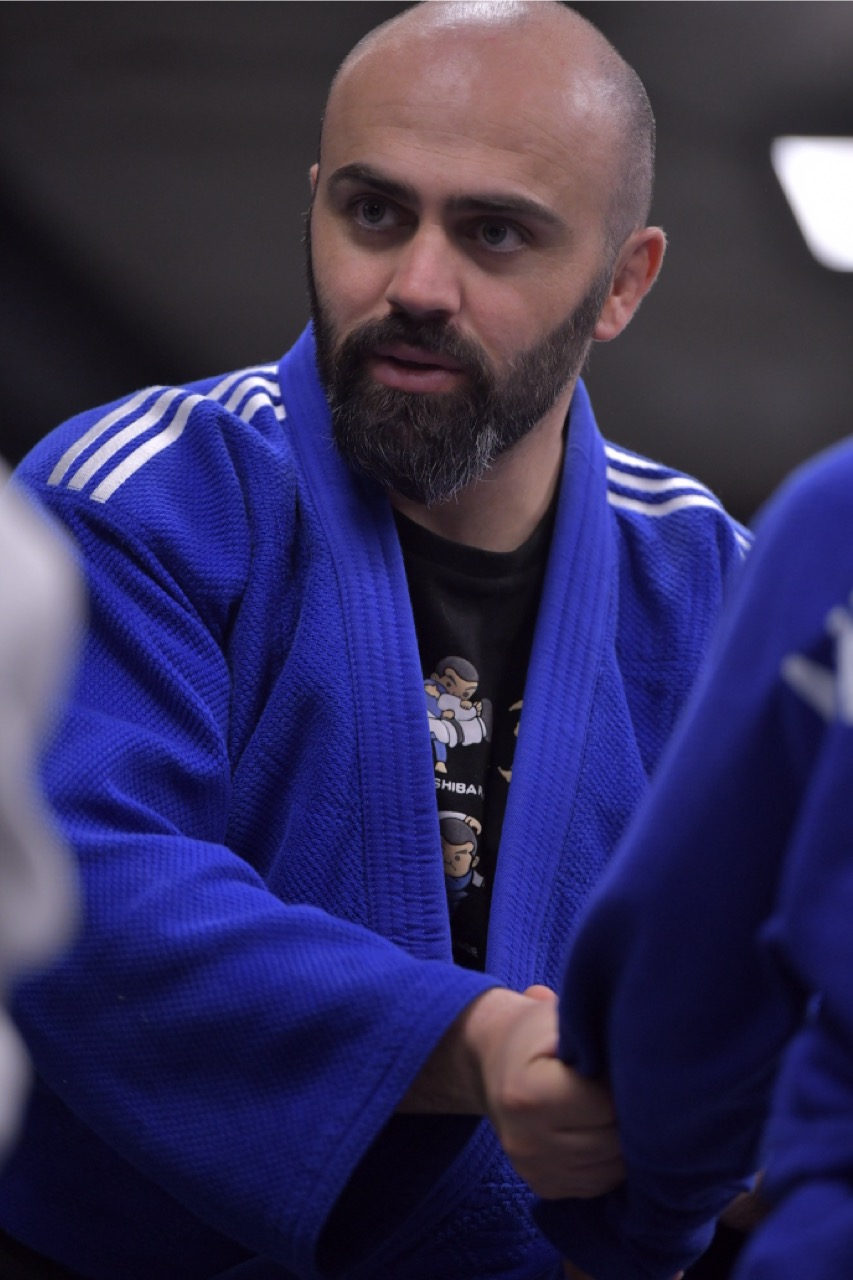 Judo coach explaining technique to adult athletes on the mat